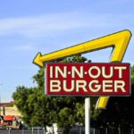 In-N-Out Burger sign with yellow arrow against blue sky