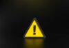 Yellow triangular warning sign with exclamation mark on black background
