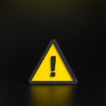 Yellow triangular warning sign with exclamation mark on black background