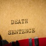 Typewriter typing the words death sentence on paper