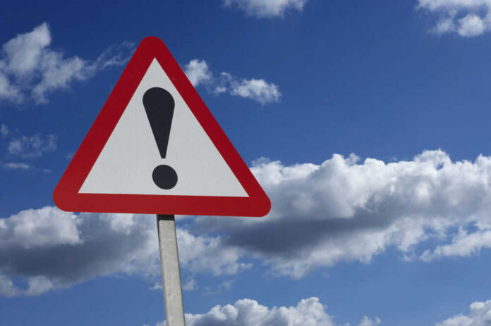 shutterstock_539658352 Warning sign with exclamation mark against sky