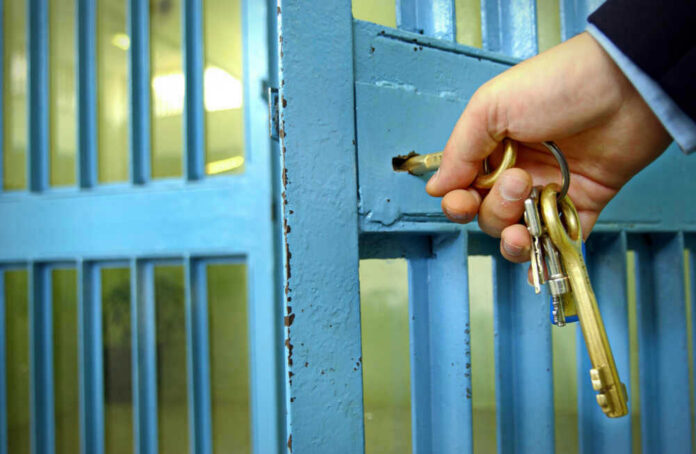 shutterstock_789621847 Hand unlocking blue metal door with keys.