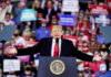 Donald Trump speaking at a rally with arms outstretched