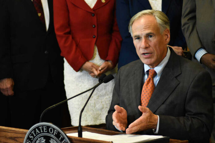 shutterstock_1127794850 Greg Abbott speaking at a podium with a microphone
