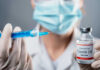 Doctor holding COVID-19 vaccine vial and syringe.