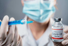 Doctor holding COVID-19 vaccine vial and syringe.