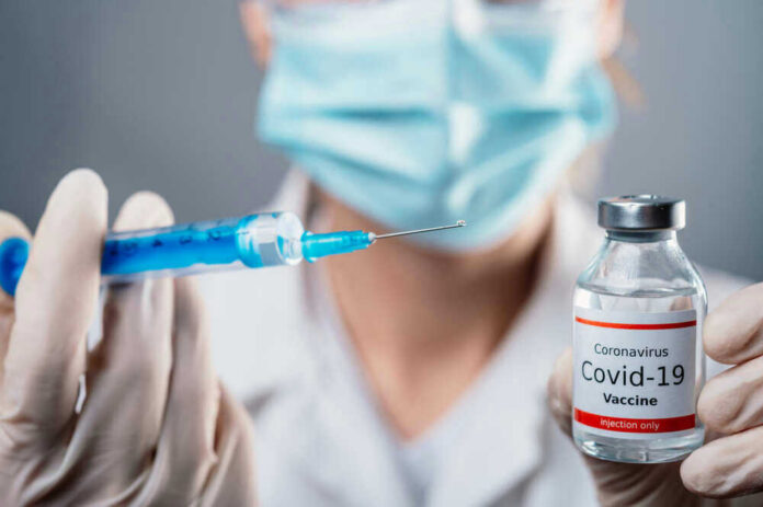 Doctor holding COVID-19 vaccine vial and syringe.