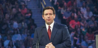 Ron DeSantis at a podium during an event; Christian Jones not visible