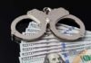 Handcuffs resting on a stack of hundred dollar bills