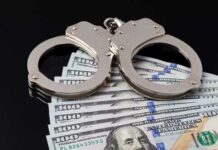 Handcuffs resting on a stack of hundred dollar bills