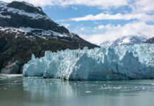Glacier with mountains and cloudy sky in background