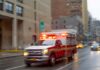 Ambulance with flashing lights driving on a wet city street