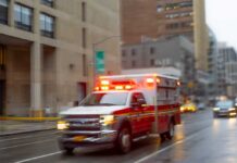 Ambulance with flashing lights driving on a wet city street