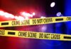 Crime scene tape with police lights in the background