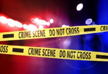 Crime scene tape with police lights in the background