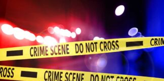 Crime scene tape with police lights in the background
