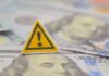 A warning sign placed on top of U.S. dollar bills