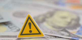 A warning sign placed on top of U.S. dollar bills