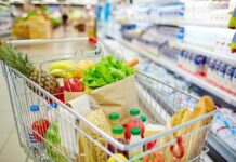 A shopping cart filled with fresh fruits, vegetables, and groceries